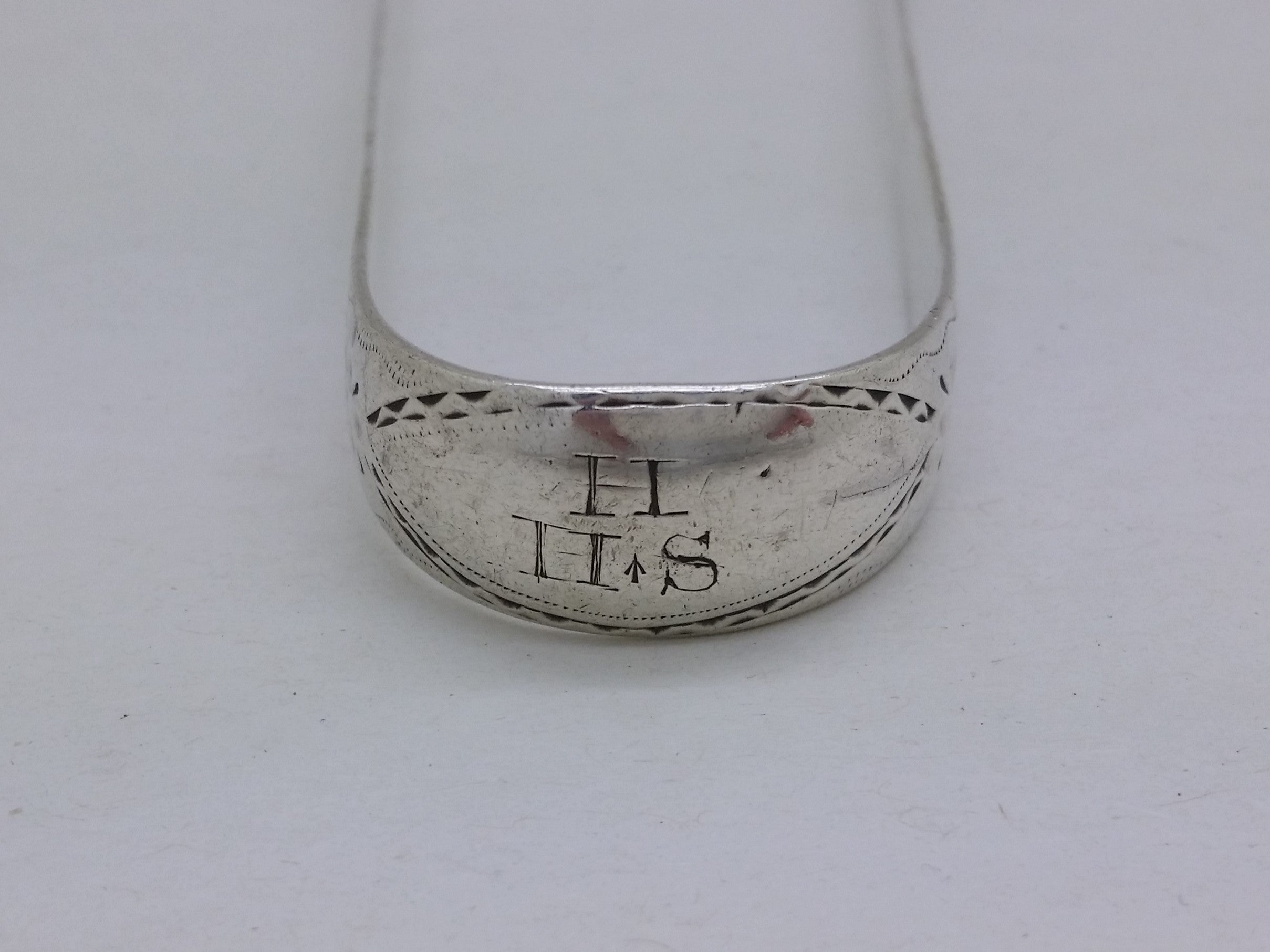 Bow of sterling silver sugar tongs with matrimonial initial inscription H over H S, with the first letter denoting the surname, and the two letters together denoting the Christian names of the wedded couple.
