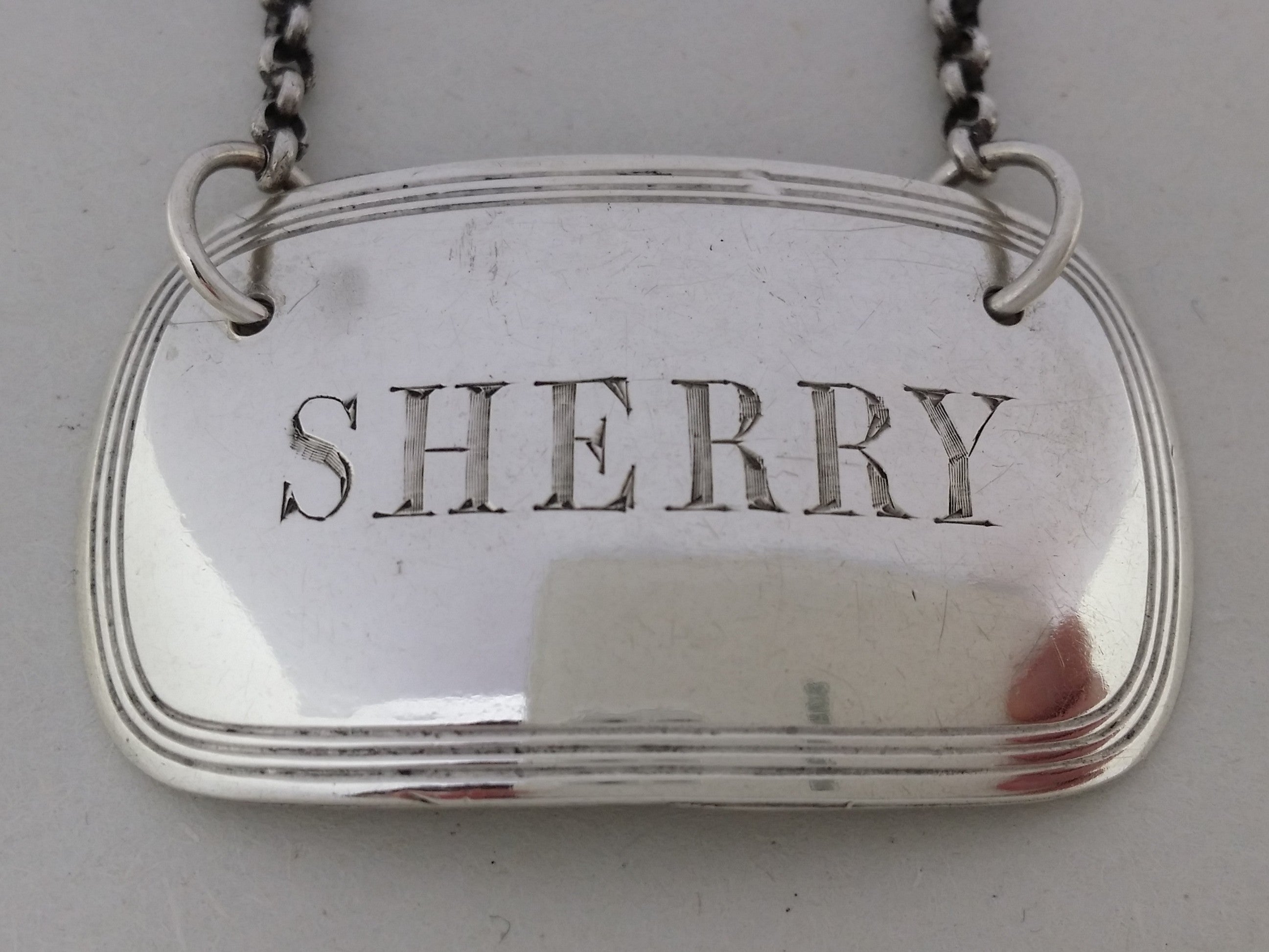Close-up of the decanter label, showing the hand-cut letters SHERRY, and triple thread border.