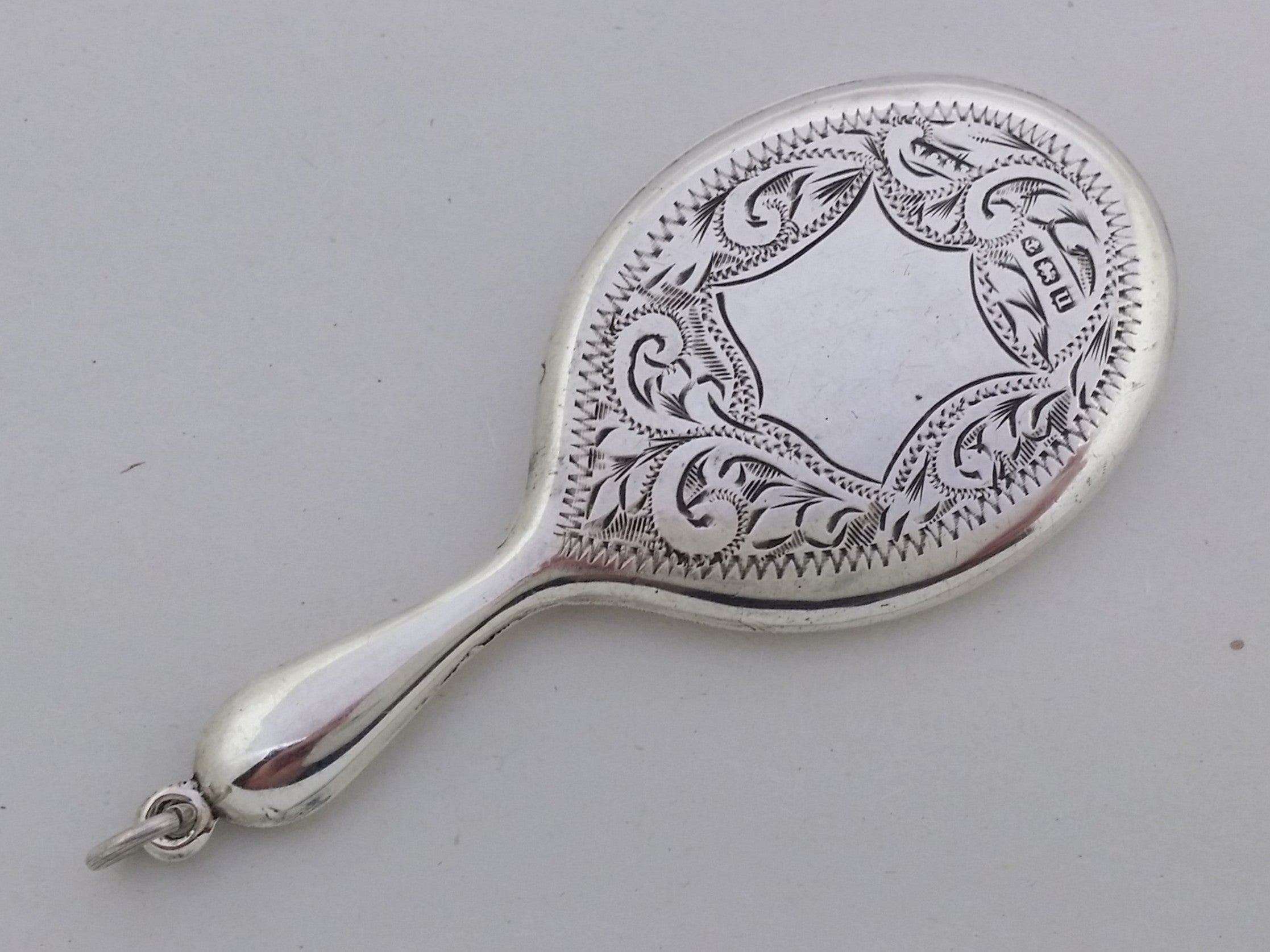 Miniature sterling silver mirror with engraved acanthus decoration, a central vacant shield cartouche, and wrigglework edging.
