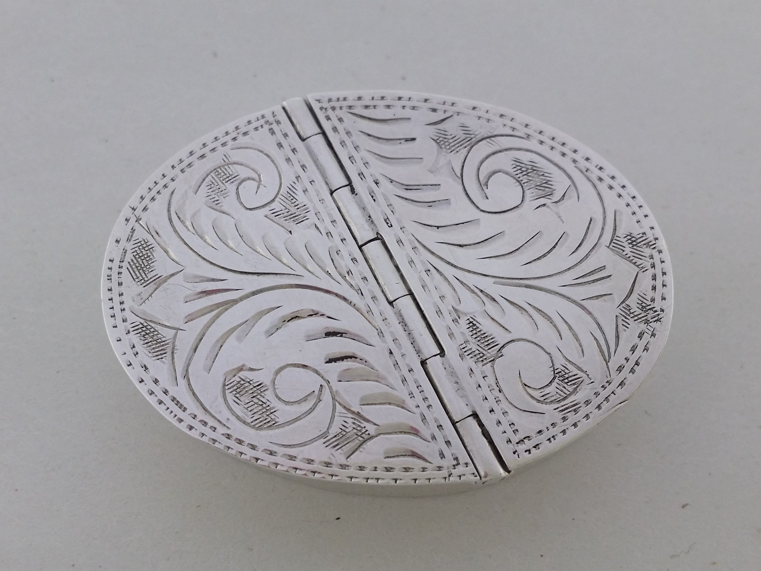 Pill box foliate engraved double hinged lids with stippled edging.