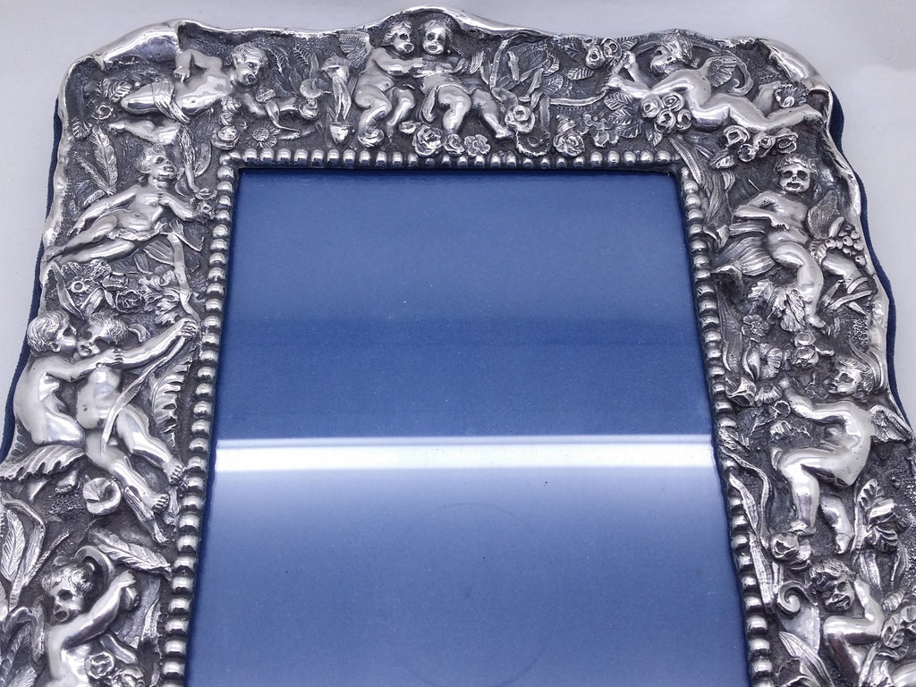 Upper part of electroformed filled britannia silver photo frame of high-relief winged cherubs, within a floral & foliate setting.