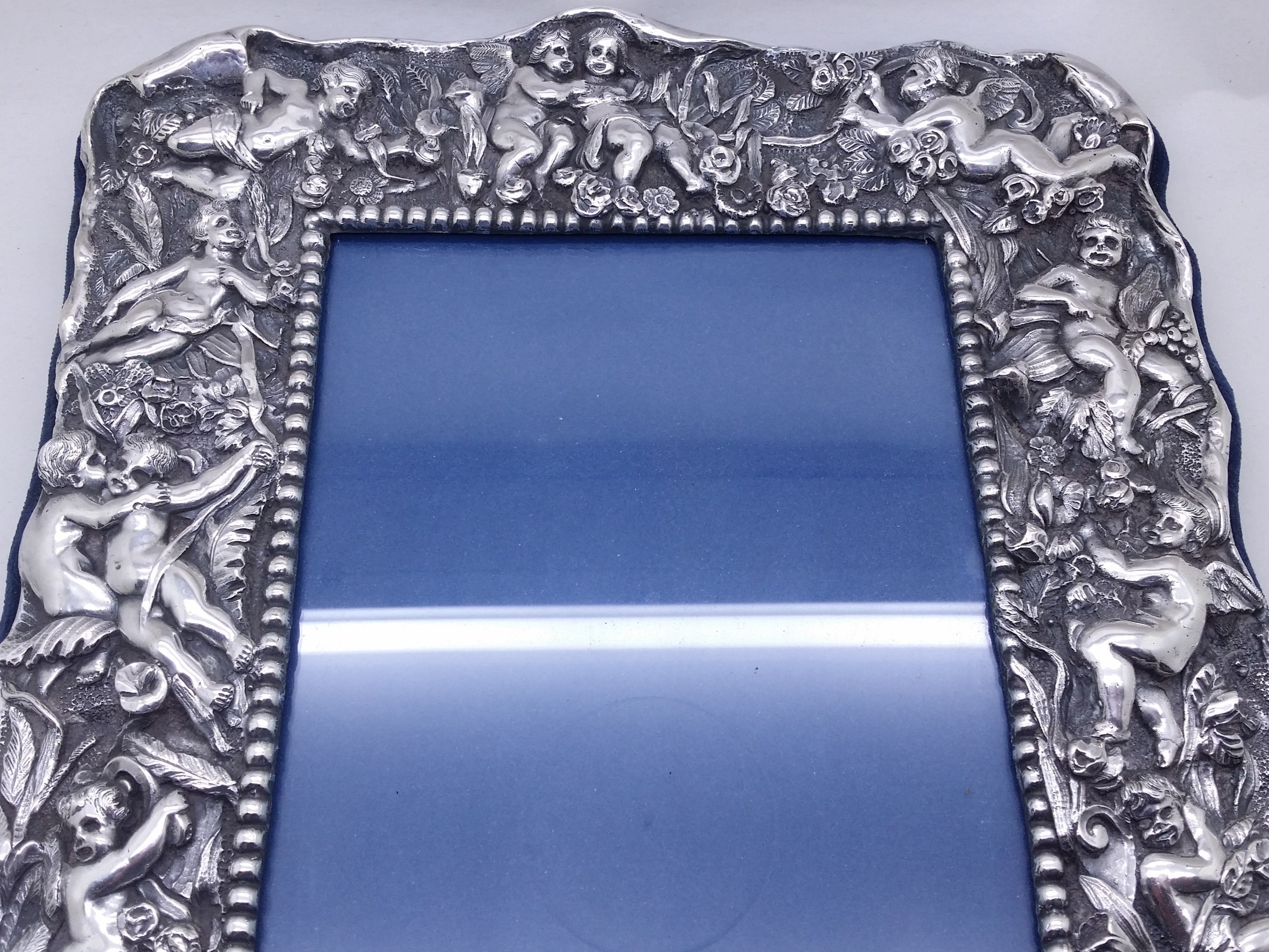 Upper part of electroformed filled britannia silver photo frame of high-relief winged cherubs, within a floral & foliate setting.