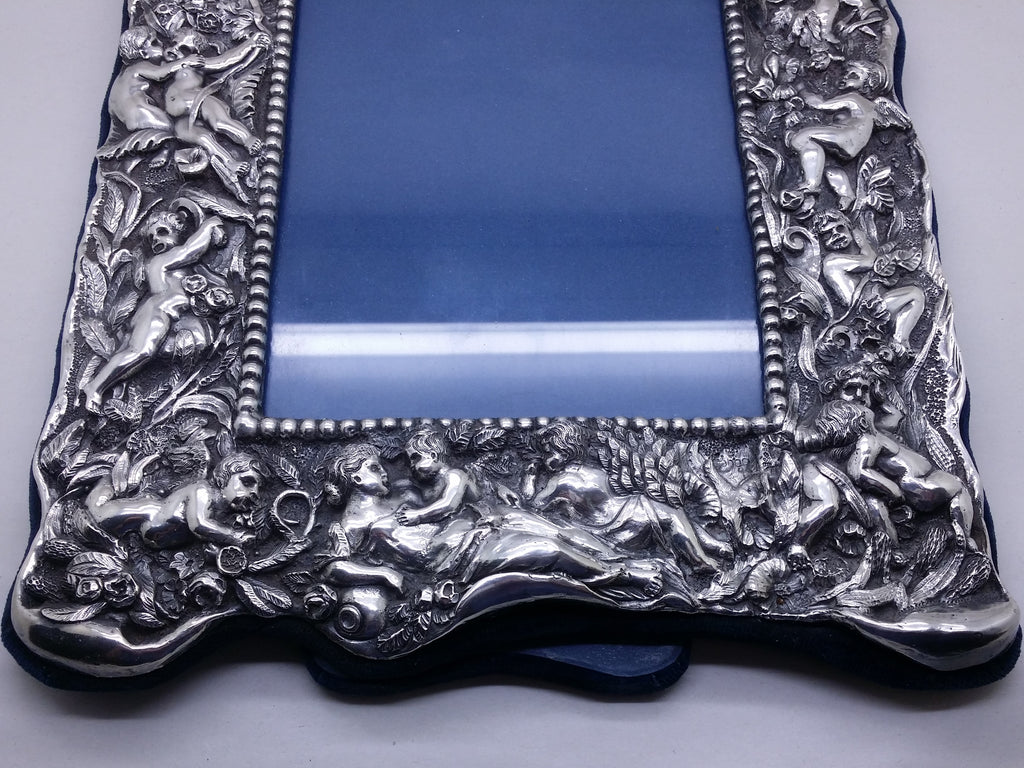 Lower part of electroformed filled britannia silver photo frame of high-relief winged cherubs, within a floral & foliate setting.
