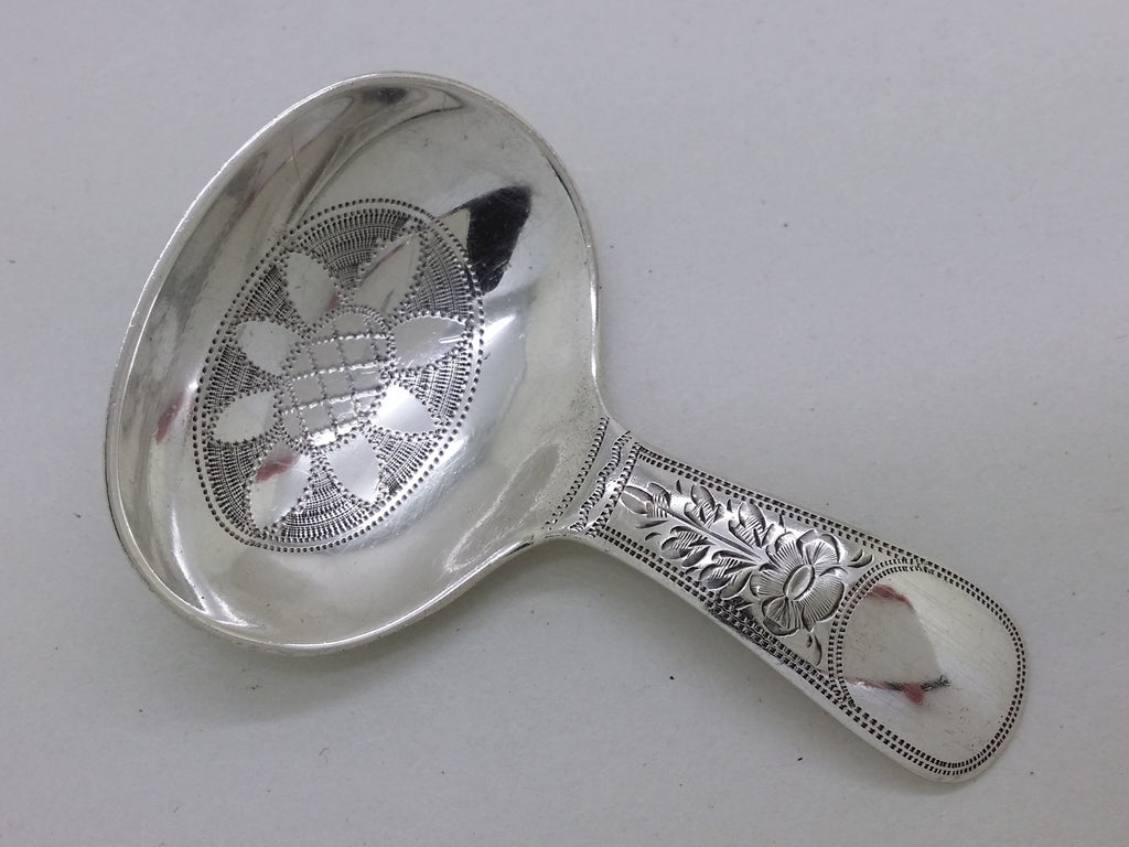 Sterling silver caddy spoon with floral engraved tab handle with a vacant cartouche, and stippled edging.