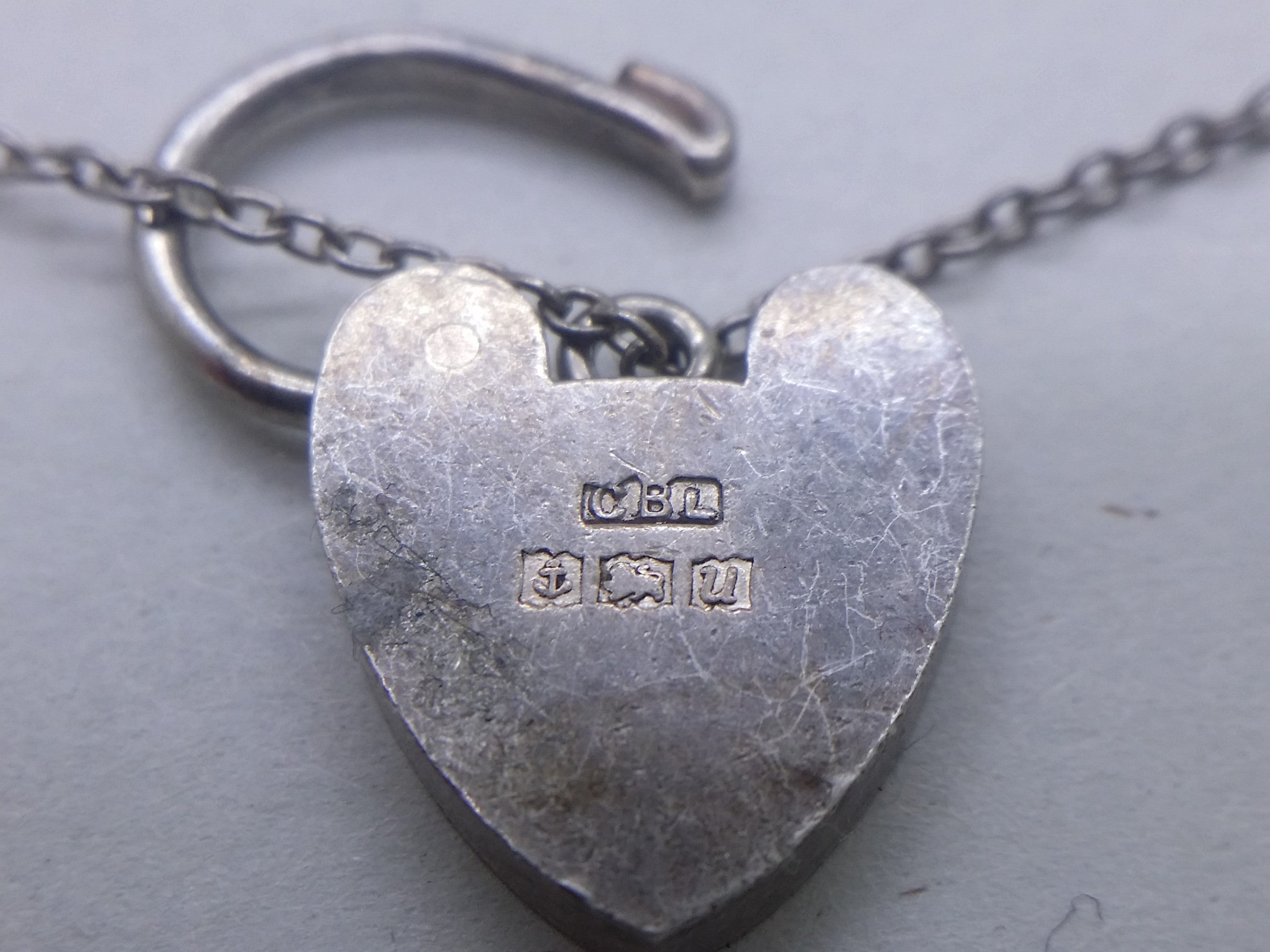 Charm bracelet padlock hallmarks: Clarke Brothers (Liverpool) Ltd maker's mark CBL; anchor mark for Birmingham; lion passant mark for sterling silver; and Birmingham date letter U for 1969.