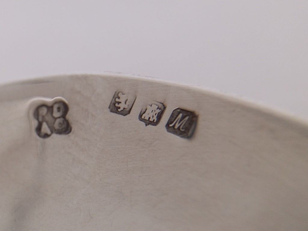 Souvenir spoon hallmarks: Isle of Mull Silver Co maker's mark PDAC; lion rampant mark for scottish sterling silver; three towered castle mark for Edinburgh; and UK date letter M for 1986.