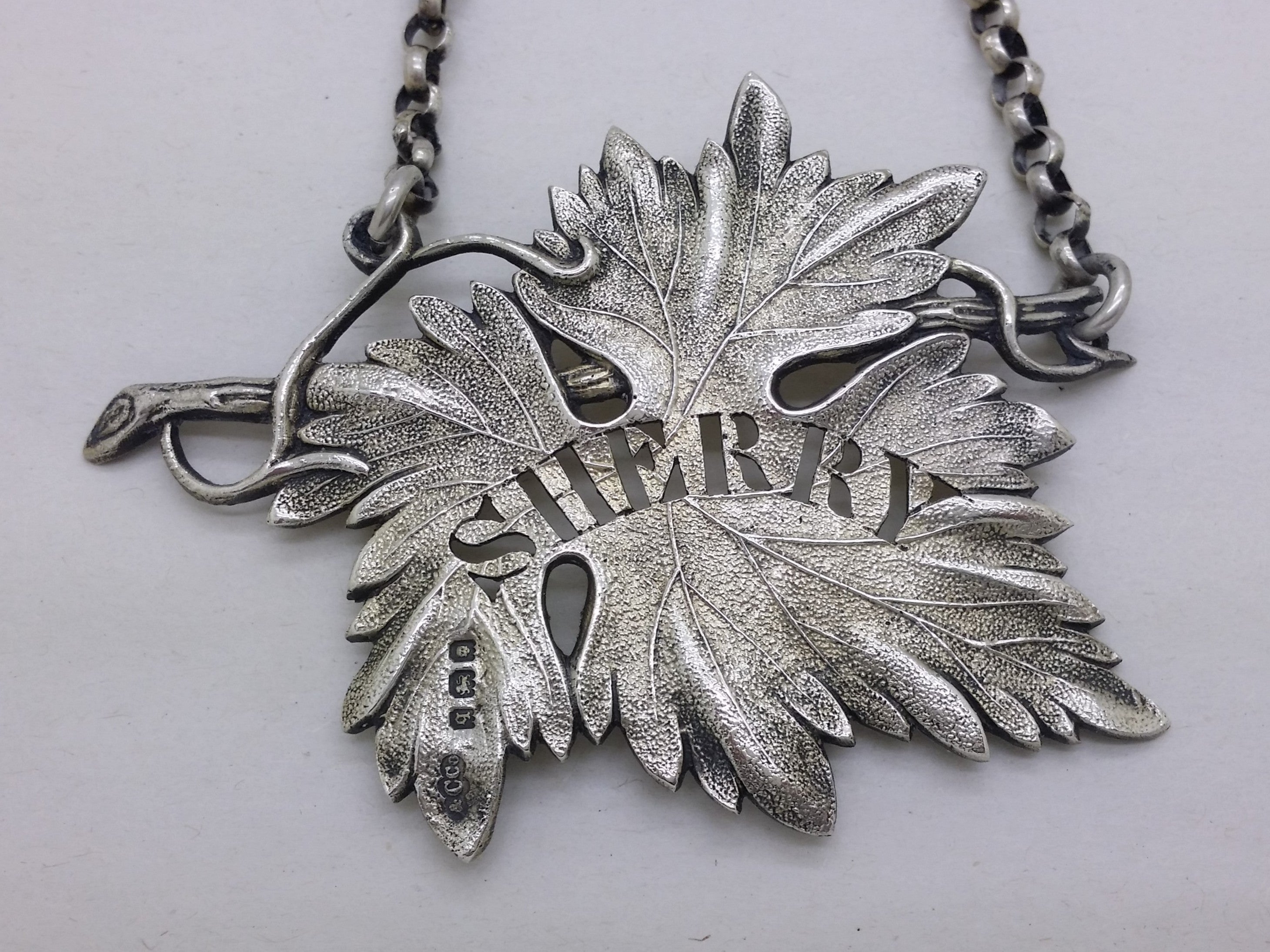 Close-up of the vine leaf shaped decanter label, showing the pierced cut-out letters SHERRY.