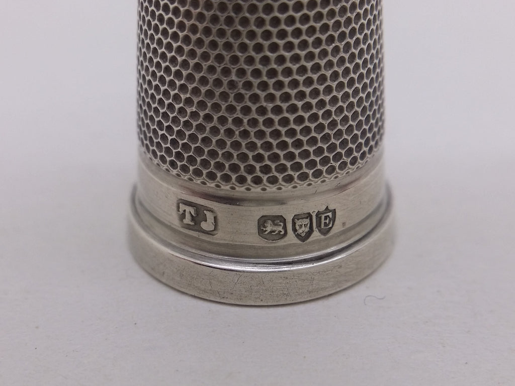Thimble hallmarks: Johnson, Sons & Edmunds maker's mark TJ for Thomas Johnson; lion passant mark for sterling silver; leopard head mark for London; and London date letter E for 1880.