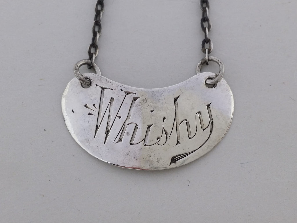 Close-up of the kidney shaped decanter label, showing the hand-cut letters Whishy, instead of Whisky.