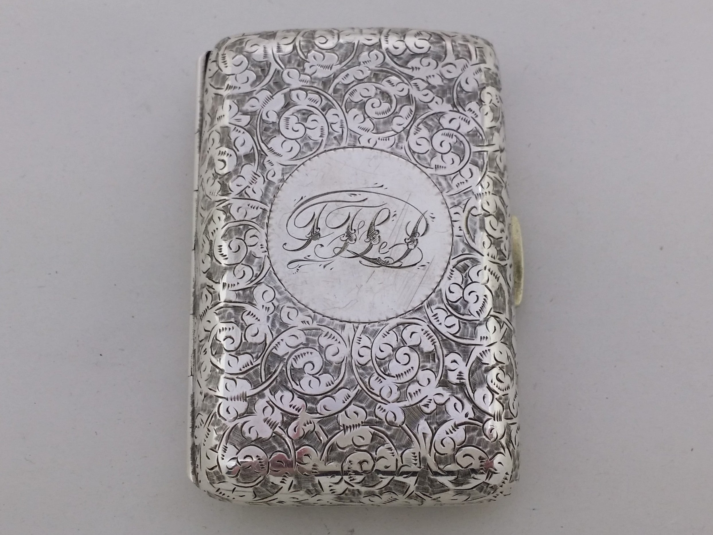 Sterling silver cigarette case with engraved acanthus scrolled decoration, and an inscribed circular cartouche TFLP