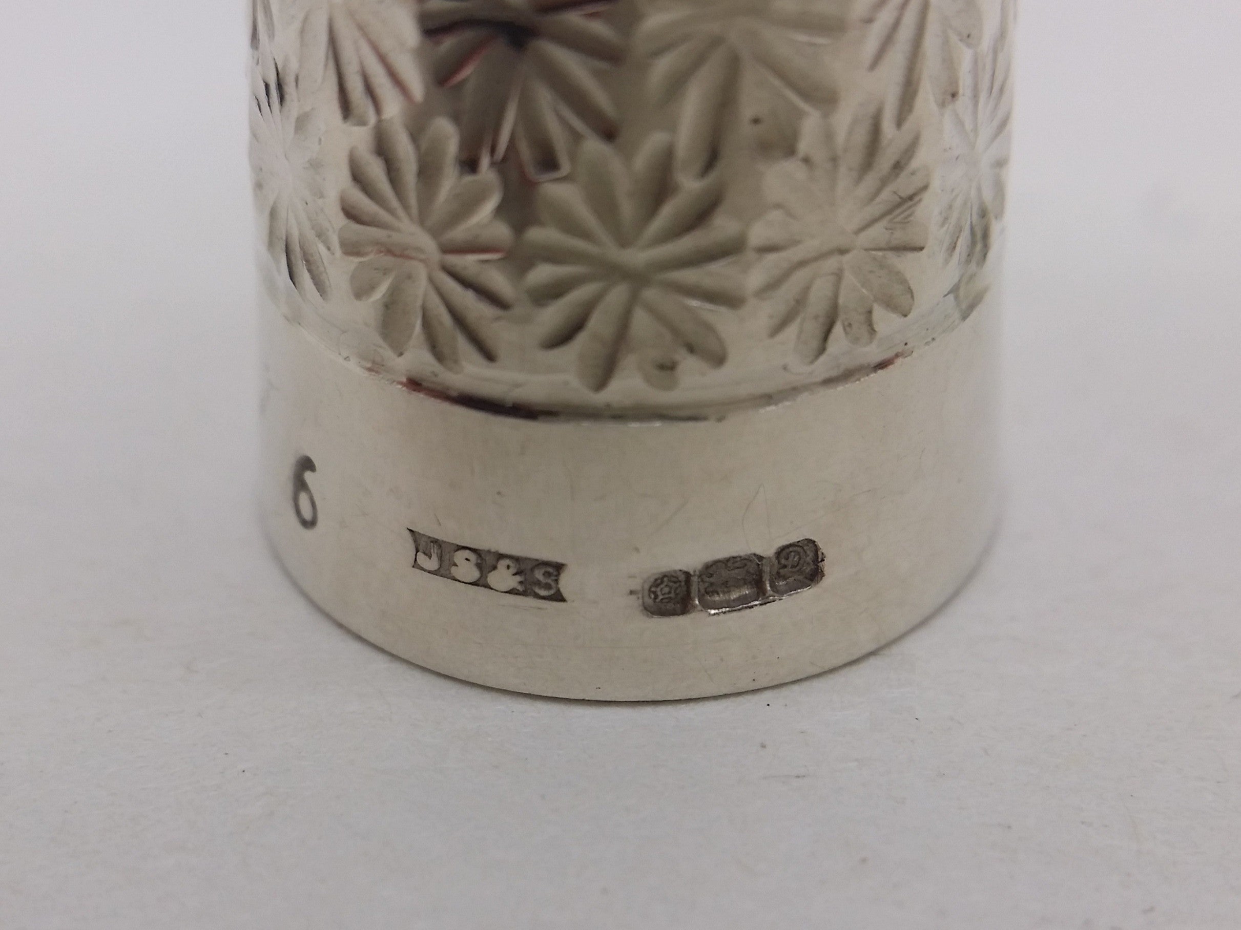Thimble hallmarks: Size 6 mark; James Swann & Son maker's mark JS&S; Tudor rose mark for Sheffield; lion passant mark for sterling silver; and UK date letter D for 1978.