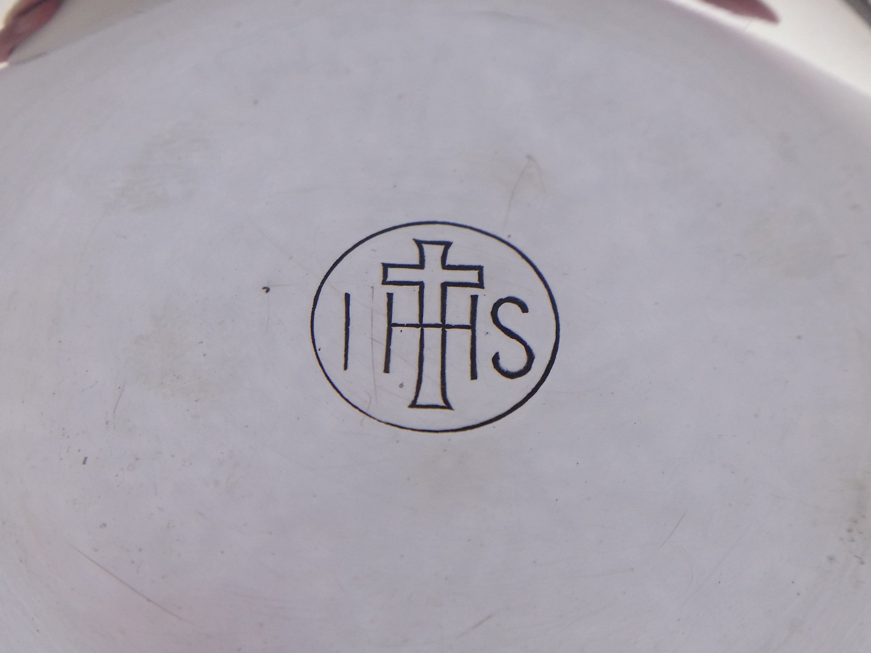 Circular cartouche with a cruciform, and the Christogram IHS, on sterling silver communion paten dish.